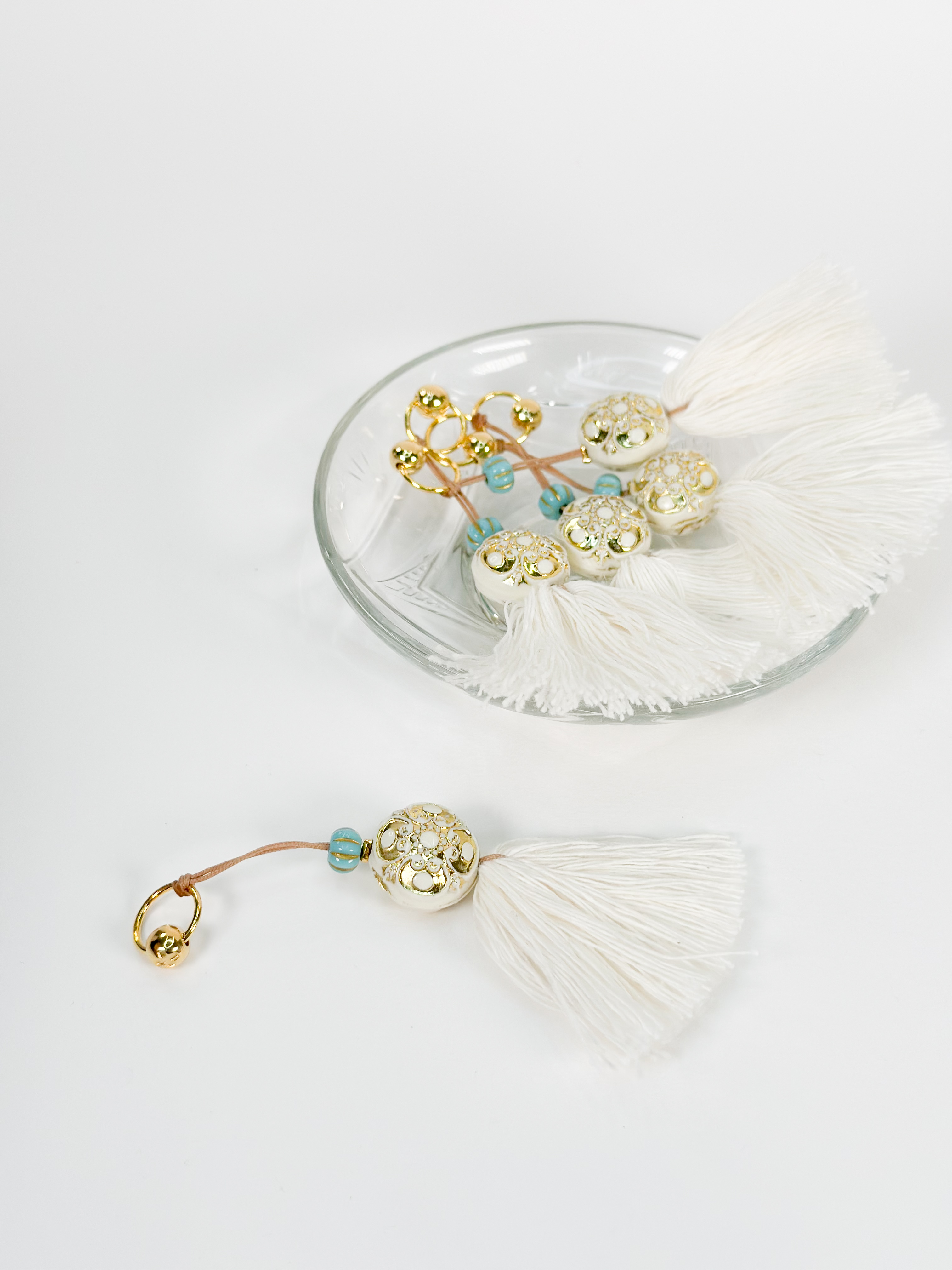 CELFIE CO - Μαρτυρικό μπρελόκ με χειροποίητη εκρού φούντα και στρογγυλό επιχρυσωμένο σταυρό